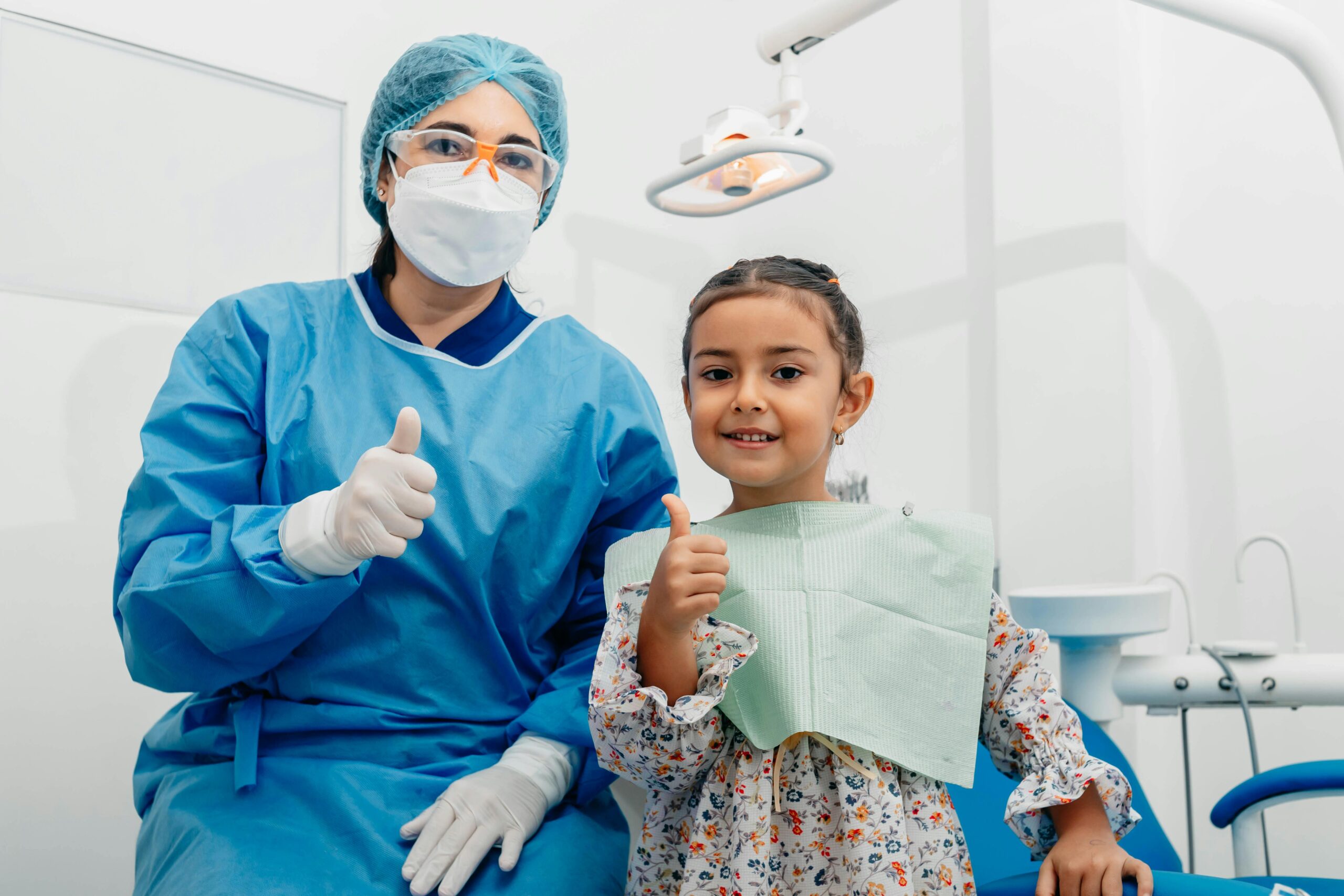 Child and dentist smiling with thumbs up at a dental clinic in Ecuador.