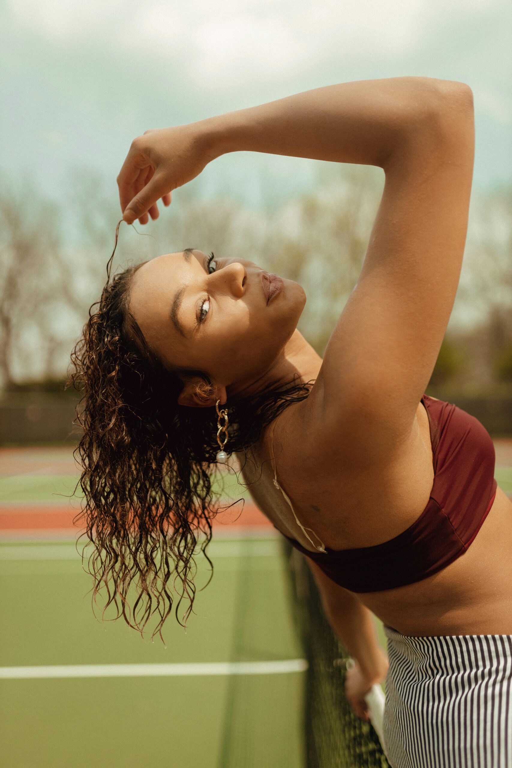Fashionable woman posing on a tennis court in Des Moines, showcasing modern casual style.