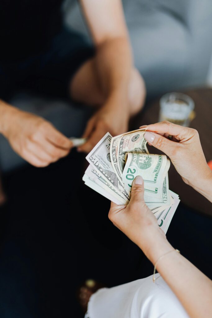 Hands exchanging cash in an indoor setting, representing financial transaction or budgeting.